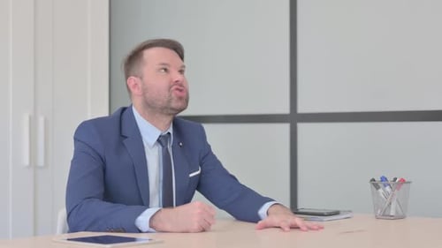 Angry Businessman in Frustration Sitting in Office