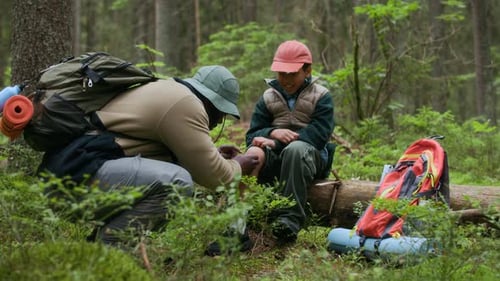 Father Putting Bandage on Son Knee During Forest Hike