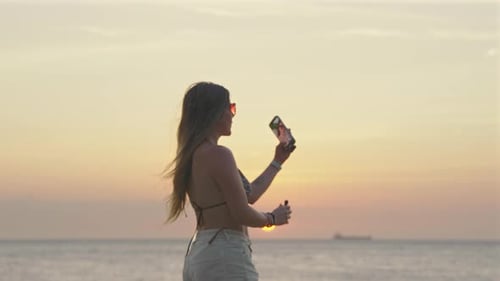Woman On A Beach At Sunset, Recording A Video With A Mobile Phone And Wireless Microphone. - slow mo