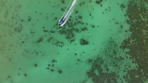 Longtail boats float on crystal clear waters near shore, Thailand