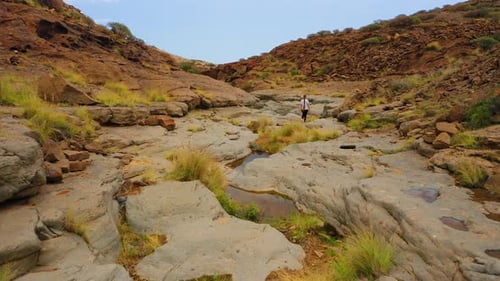 Aerial View of Lonely Woman Hiker Explores Mountains Plains and Ravines Volcanic Rocks with