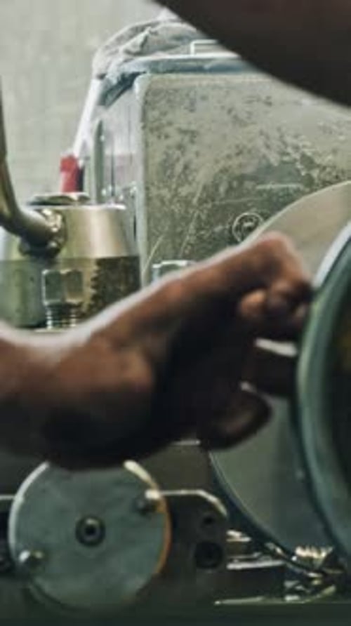 Metalworker operating lathe machine in workshop, close-up shot