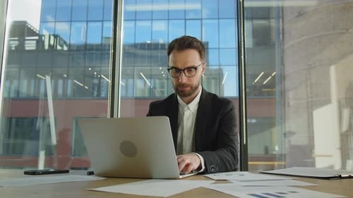 Focused Businessman Working at Desk with Laptop