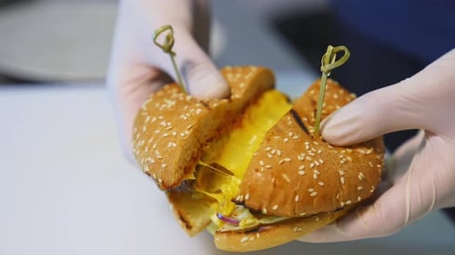 Gloved Hands Separate Yummy Burger to Show Cheese