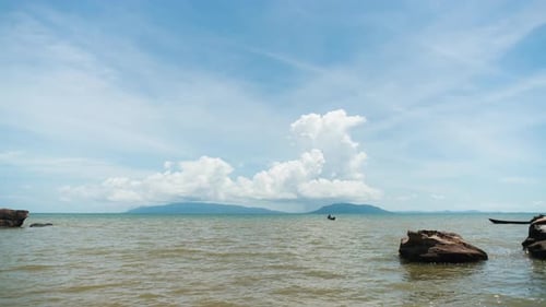 Seascape time lapse of island on the ocean horizon with cloud formations on blue sky over the hills