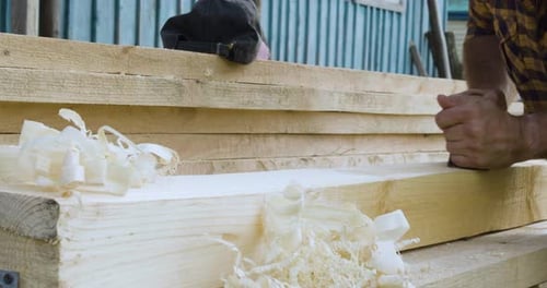 Man Smoothing Wooden Plank with Hand Plane Outside