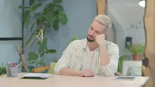 Joven moderno que duerme sentado en el trabajo