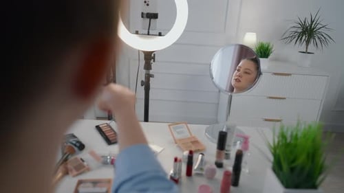Alegre artista de maquillaje archivando un tutorial en vídeo para un blog en las redes sociales en Studio Influencer