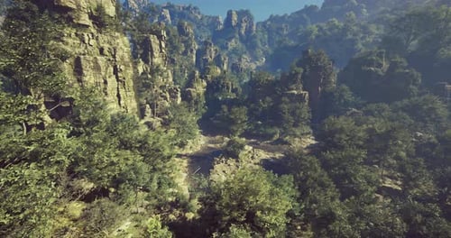 Lush Green Valley Surrounded By Towering Rock Formations in Bright Daylight