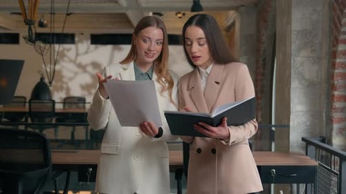 Women Discussing Documents in Modern Office Setting