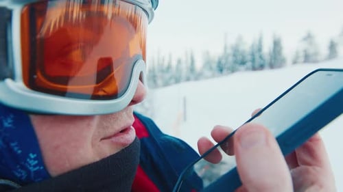 Skier Using Smartphone on Snowy Mountain