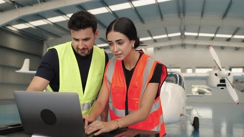 Aircraft Maintenance Crew Working on Laptop in Hangar