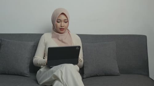 Woman Sits On Couch Using Tablet Device