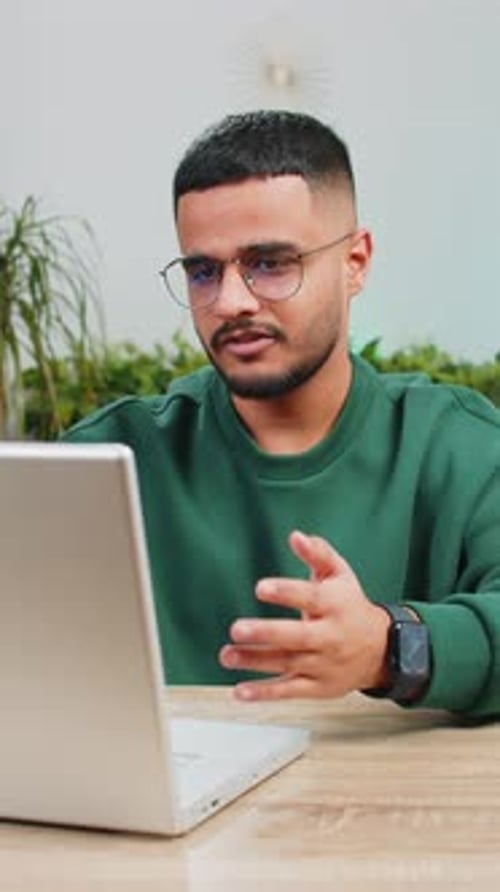 Young Man Video Conferencing at Desk with Laptop