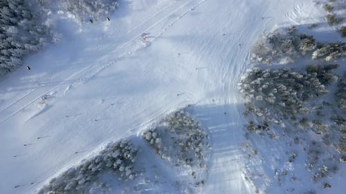 Top View of Snowy Ski Slope with People Skiing and Chairlifts in Mountain Resort