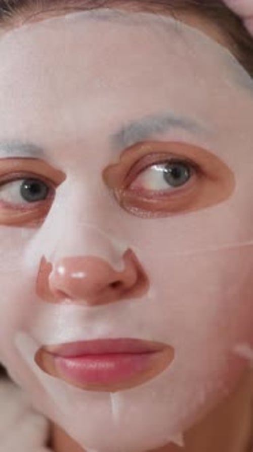 Woman Presses Sheet Mask to Face in Close-up