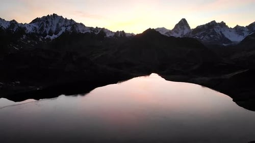 Aerial flyover over a half frozen lake during autumnn sunset in the Alps