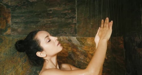 Woman Enjoys Shower with Water Running Over Her Arms