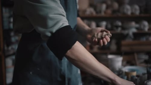 Closeup Sculptor's Hands Wet Clay with Water to Give It a Desired Shape While Working in Workshop