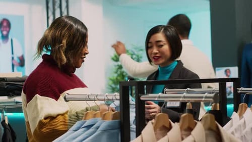 Asian Employee Showing Clothes to Customer in Retail Shop