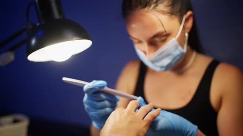 Woman Files Nails with Nail File Indoors