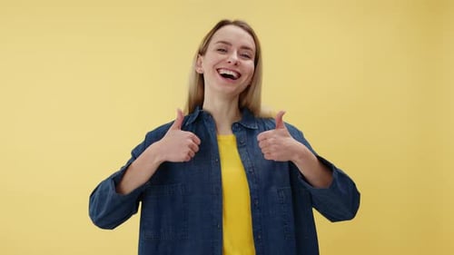 Smiling Woman Gives Thumbs Up on Yellow Backdrop