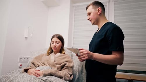 the patient is lying in the hospital in the clinic a doctor with a tablet in his hands is discussing