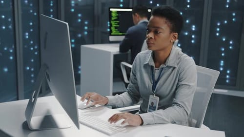Woman Typing at Computer in Modern Data Center
