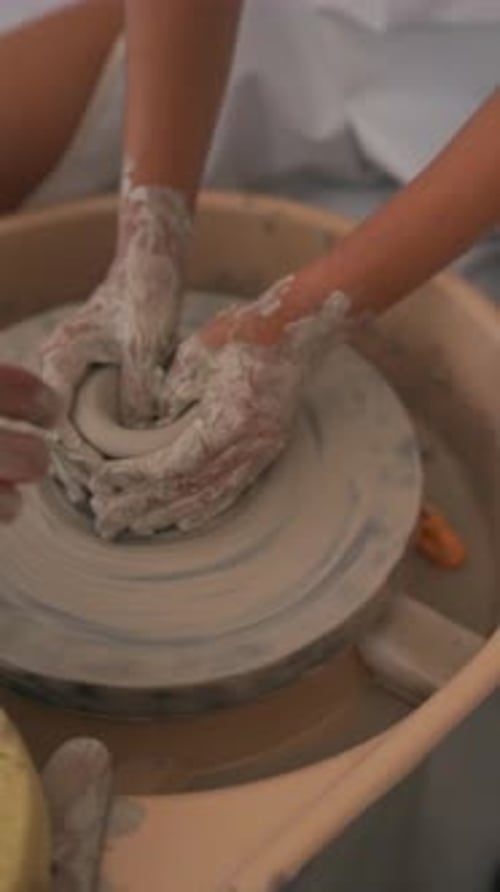 Hands molding clay on pottery wheel in studio