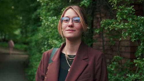 Cheerful and Beautiful Young Caucasian Woman with Glasses and a Smile on Her Face Looking at the