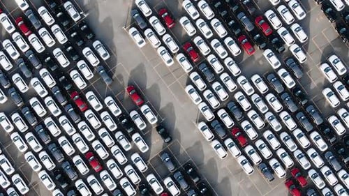 Motion over rows of finished cars of different colours at huge open warehouse