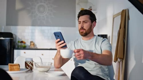 Man Using Phone and Drinking Coffee at Breakfast
