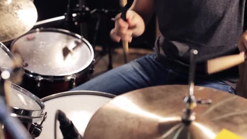 Energetic male musician plays drums and cymbals live at a rock concert