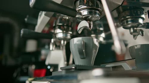 Pouring coffee flows from the machine into the cup making hot drink using the filter holder freshly