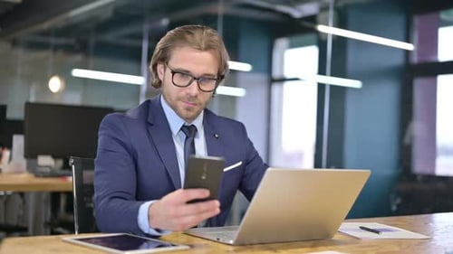 The Businessman Using Smartphone and Laptop in Office