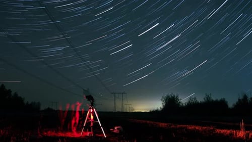 Hyperlapsus d'étoiles tournant dans le ciel nocturne et de personnes debout sur le pré et les regardant