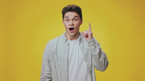 Joven guapo con expresión neutra sobre fondo amarillo brillante