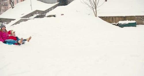 Woman and Child Sledding in a Snowy Park