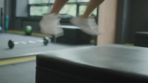 Legs of Sportswoman Jumping on Box in Gym