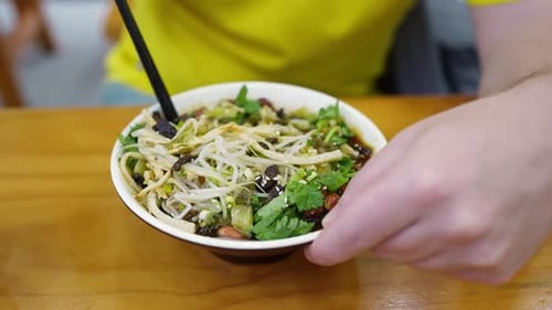 Man Eats Noodles and Sprouts With Chopsticks
