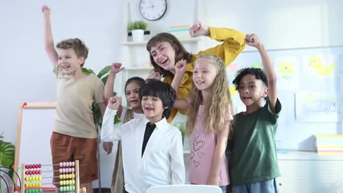 Teacher and Children Cheerfully Raising Arms in Classroom