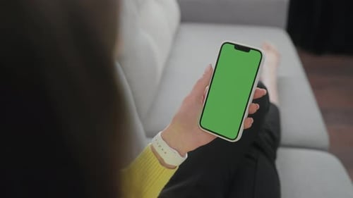 Lady Sitting on Sofa and Resting Looking and Holding Phone with Green Screen