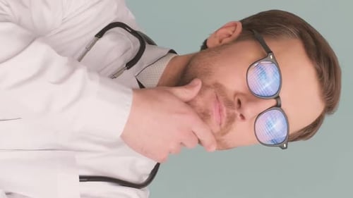 Serious Thoughtful Bearded Doctor Standing on Blue Background in Medical Uniform Vertical Video