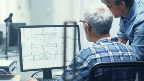 Two Senior Architectural Engineers Working With Building Blueprint on a Personal Computer. They Act