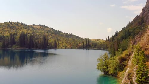 Imagem de rastreamento do belo lago Sary-Chelek, colinas arborizadas e cordilheiras pitorescas