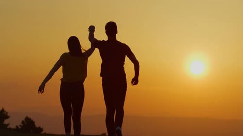 Couple Running Hand in Hand at Sunset