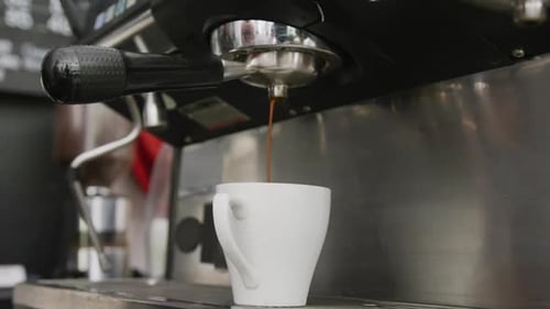 Close up of working coffee machine pouring fresh coffee into cup at cafe