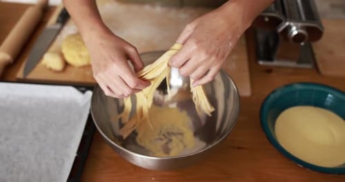 Close-up of Woman Flourishing Freshly Made Tagliatelle Pasta into a Bowl