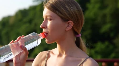 Caucasian Pretty Fit Female Athlete Standing in City Drinking Water From Bottle After Workout on