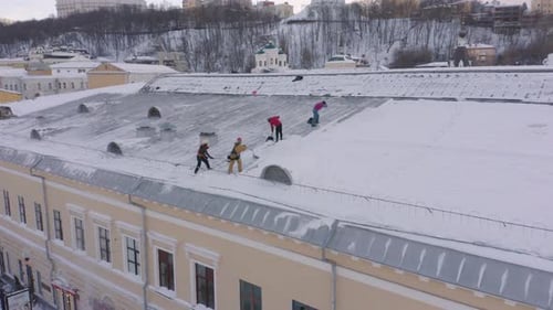 Une escouade de concierges balaie la neige sur le toit